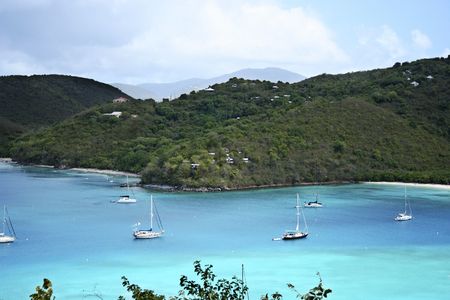 A picturesque Caribbean aqua blue bay lined with white sand beaches and dotted with sail boatsの写真素材