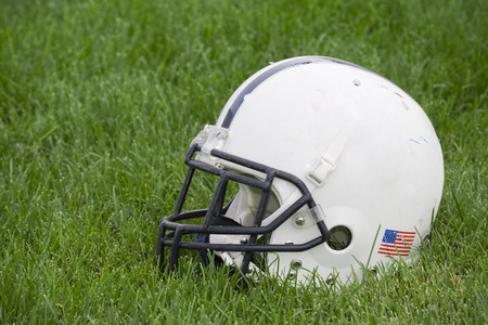 The side view of an American football helmet on a grass field.の写真素材