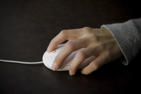 A female hand using a computer mouse to surf the internetの写真素材