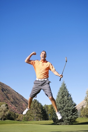 A young golfer jumping in the air in excitement about making a putの写真素材