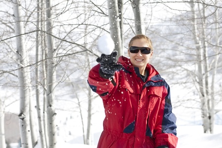 Woman Throwing a Snowball Outdoorsの写真素材