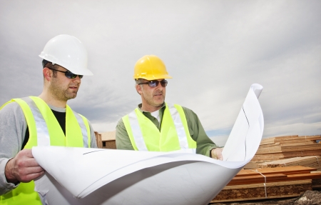 Two contractors reading construction plans at worksiteの写真素材