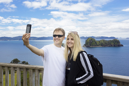 Couple on vacation taking photo of beautiful ocean view