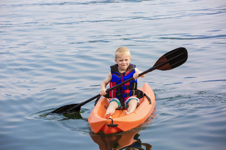 Young Boy paddling a kayak on a beautiful lakeの写真素材