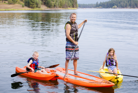 Attractive family kayaking and paddle boarding together on a beautiful lakeの写真素材