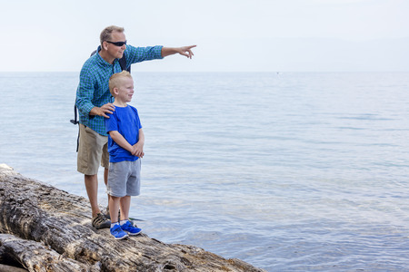 Father and son hiking together along a scenic lake. Lots of copy space and full length photoの写真素材