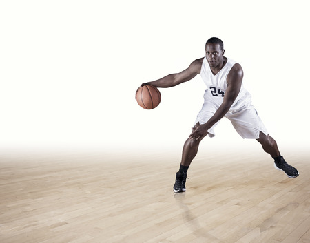 A strong athletic professional basketball player skillfully dribbling up the court. Clean white background. Lots of copy spaceの写真素材