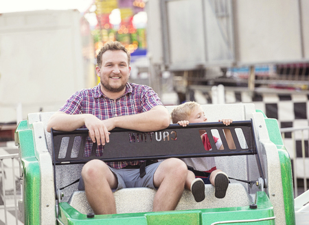 Smiling father and son on an Amusement Park Ride together