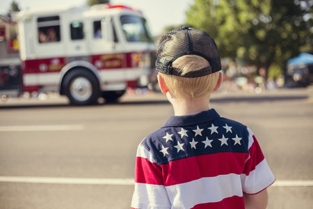 Kids watching an Independence Day Parade and a ambulance drives by