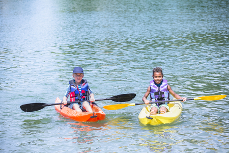 Two diverse boys kayaking together on the lakeの写真素材