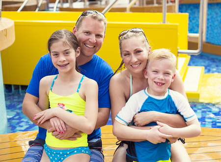 Smiling cute young family enjoying a day at the pool while on a tropical cruise vacation together. Happy and smiling on a warm day swimming togetherの写真素材