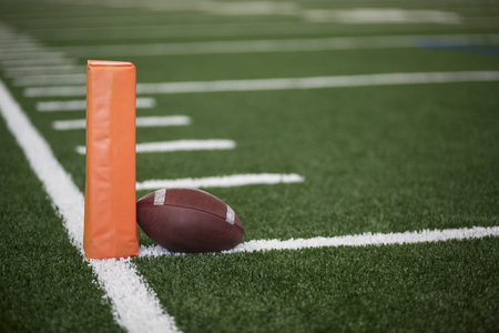 Ball resting on the goal line of a Football field endzone next to an orange pylonの写真素材