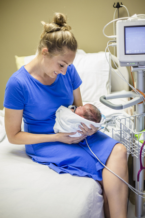 Smiling Mother holding her newborn premature baby in the hospitalの写真素材