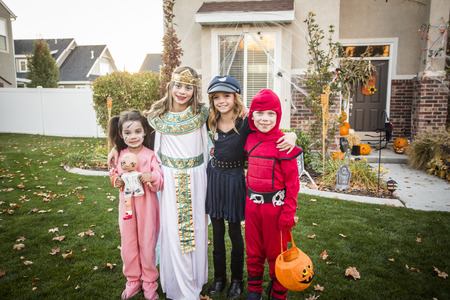Group of kids dressed in Halloween costumes going trick or treating outdoors in October in a decorated neighborhoodの写真素材