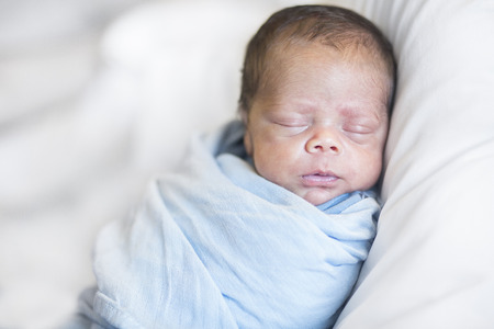 Cute bi-racial Newborn baby boy sleeping in a blanketの写真素材