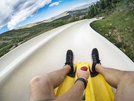 Point of view photo of a man riding down an downhill alpine slide on a fun summer vacation in the mountainsの写真素材