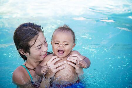 Two cute kids playing in a swimming pool on a sunny day while on vacation. Bright colorful fun summer photo with copy spaceの写真素材