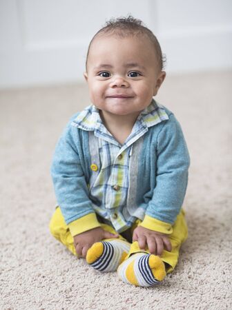 Beautiful smiling diverse baby boy portrait. Full length photo of an adorable child sitting indoorsの写真素材