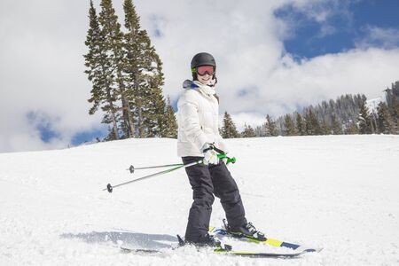 young smiling teenage female skier learning to ski at a ski slope with the on a fun winter day at the ski resortの写真素材