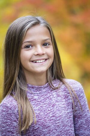Beautiful Portrait of smiling little girl outdoors. Taking a cute picture on a warm fall day. Girl looking at the camera with a gorgeous grinの写真素材