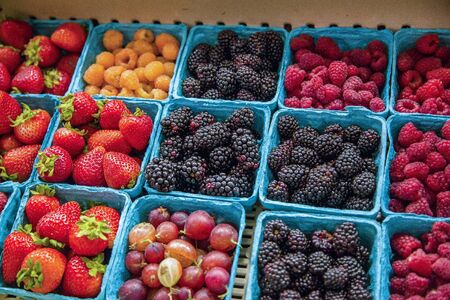 A variety of berries and fruits for sale at a grocery store. Fresh organic strawberries,...