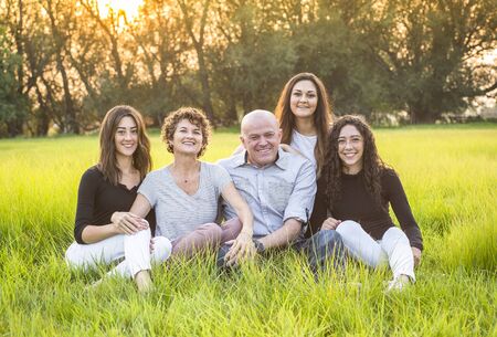 Attractive Smiling beautiful family sitting together outdoors in a grass field. Happy family...