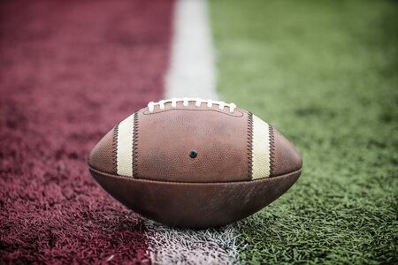 Closeup of an American Football resting on the goal line at a football stadium. Looks like its a...