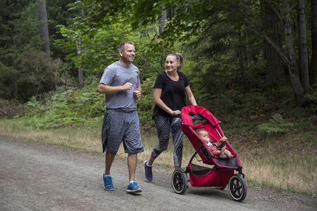 Couple exercising and jogging together pushing their baby in a strollerの写真素材