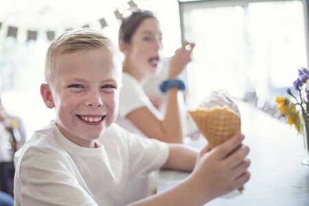 Smiling Children enjoying ice cream cones at an ice cream parlor. Little boy with a waffle cone is enjoying some delicious ice creamの写真素材