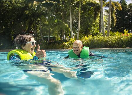 Senior couple splashing, playing, and having fun at a water park. Smiling and having a great vacation enjoying an active retirement.の写真素材