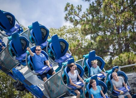 Young family having fun riding a rollercoaster at a theme park. Screaming, laughing and enjoying a fun summer vacation together.の写真素材