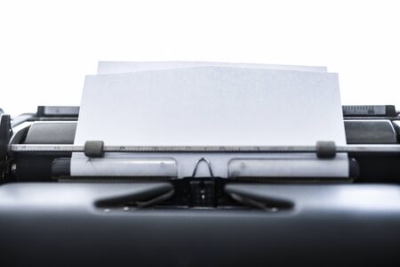 Close up view of an old school typewriter. Selective focus on the paper. Copy space on the paper for adding text. Isolated on a white background. Ready to write a story.の写真素材