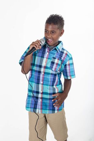 Talented young diverse singer singing into a microphone. Cute African American boy singing with emotion and performing on stage. Isolated on a white backgroundの写真素材