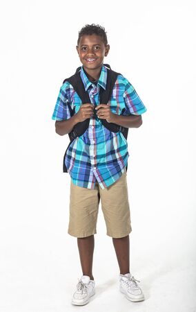 Smiling African American school boy isolated on white background. Wearing a backpack and a plaid shirt and ready to go to school. Front viewの写真素材