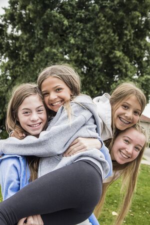 Group of teenage girls playing and smiling together outdoors. Laughing and being playful at school togetherの写真素材