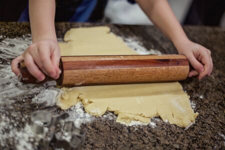 Preparing Christmas cookie dough using a rolling pin to prepare the dough. Selective focus on rolling the sugar cookie dough on the marble countertopの写真素材