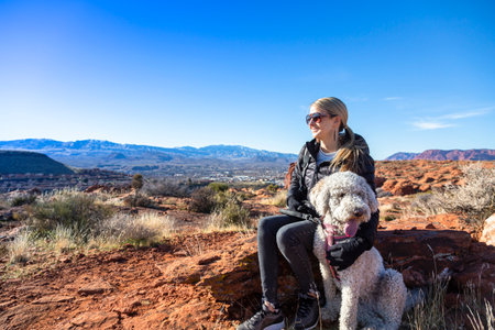 Happy woman on an outdoor hike with her dog. Enjoying nature on a sunny day. Enjoying a scenic overlook in St. George, Utahの写真素材