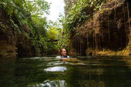 Woman swimming and floating along a beautiful tropical jungle river. Experiencing the natural beauty of Mexico.の写真素材