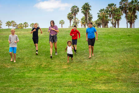 Large diverse group of active children running together in an outdoor park. Boys and girls of...