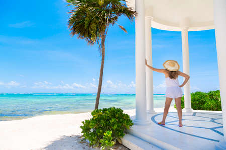 Woman in a sunhat enjoying a scenic Caribbean beach resort while on vacation.の写真素材