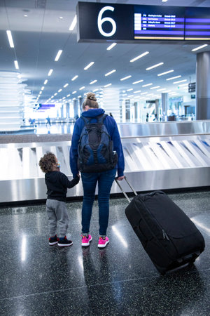 A mother and child waiting together at a baggage claim in an airport. Good air travel photo