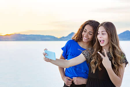 Two cute and diverse teenage girls posing and taking a selfie together outdoors on the Bonneville...