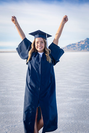 Cute Young woman in her graduation cap and gown showing excitement after graduating. Beautiful girl showing real emotion after finishing her degreeの写真素材