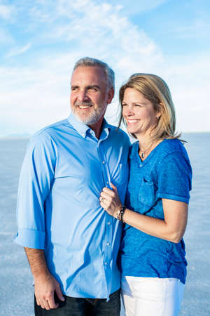 Beautiful mature couple portrait outdoors candid photo. Arms around each other and embracing with love and devotion.の写真素材