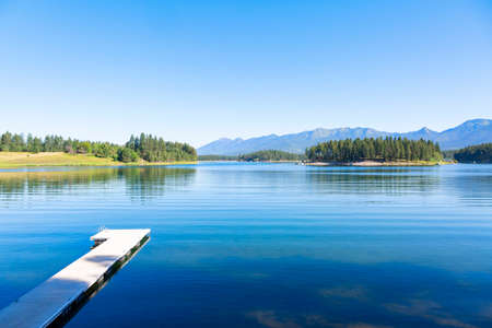 A calm beautiful scenic lake high in the Mountains of Montana called Echo Lake. A landscape photo that shows the beauty of Montana. Blue serene waters with a boat dockの写真素材