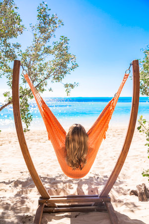Young woman relaxing in hammock on tropical beach. Vacation conceptの写真素材