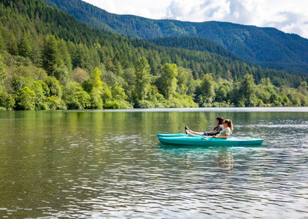 Two women Kayaking on a pristine mountain lake in the state of Washington Pacific Northwest. Scenic landscape horizontal photo of two friends enjoying the great outdoors togetherの写真素材