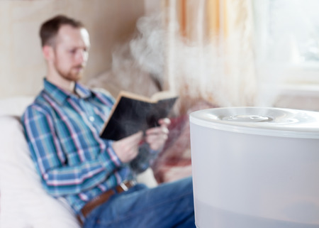 Man reading book on the blured background of humidifierの写真素材