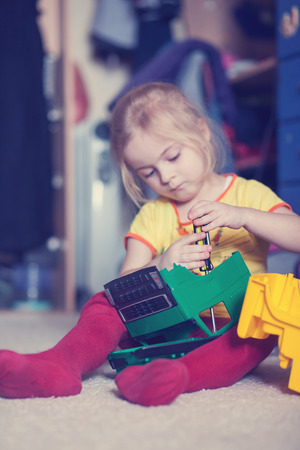Little girl repairing a toy truck cabin with a screwdriverの写真素材