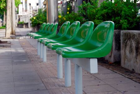 Green bench at the bus stop There is a shade of trees covered when waiting for the car to be hot.